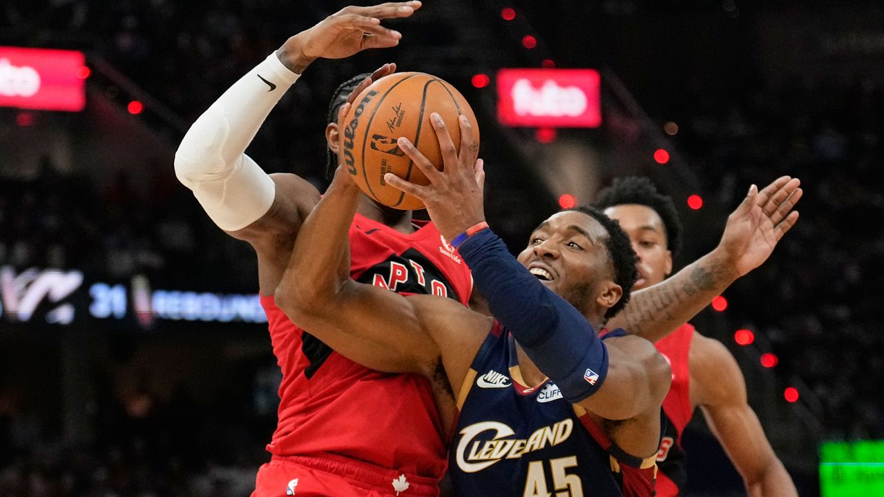 Cleveland Cavaliers guard Donovan Mitchell (45) drives past Toronto Raptors forward RJ Barrett, left, in the second half in Game 2 of a first-round NBA basketball playoffs series in Cleveland, Monday, April 20, 2026. (AP Photo/Sue Ogrocki)