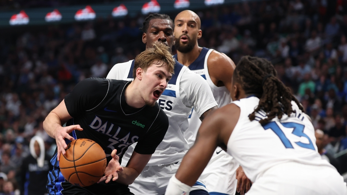 Cooper Flagg of the Dallas Mavericks drives against Ayo Dosunmu and Naz Reid of the Minnesota Timberwolves at American Airlines Center.