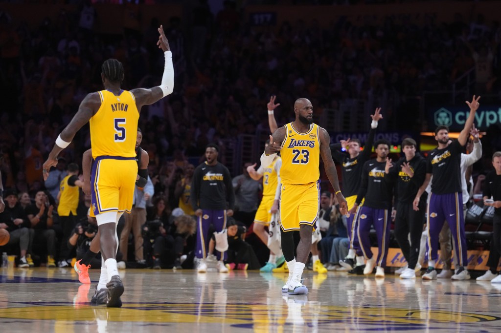 LeBron James (23) of the Los Angeles Lakers celebrates after a play with another Lakers player (5), as other Lakers players and fans cheer.
