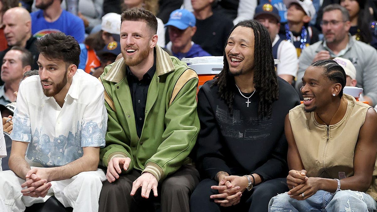 Chet Holmgren, Isaiah Hartenstein, Jalen Williams, and Shai Gilgeous-Alexander seated on the Oklahoma City Thunder bench at Ball Arena