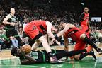 Neemias Queta of the Boston Celtics tumbles with the ball against Jakob Poeltl of the Toronto Raptors and Scottie Barne during the second half at TD Garden on April 5, 2026 in Boston. 