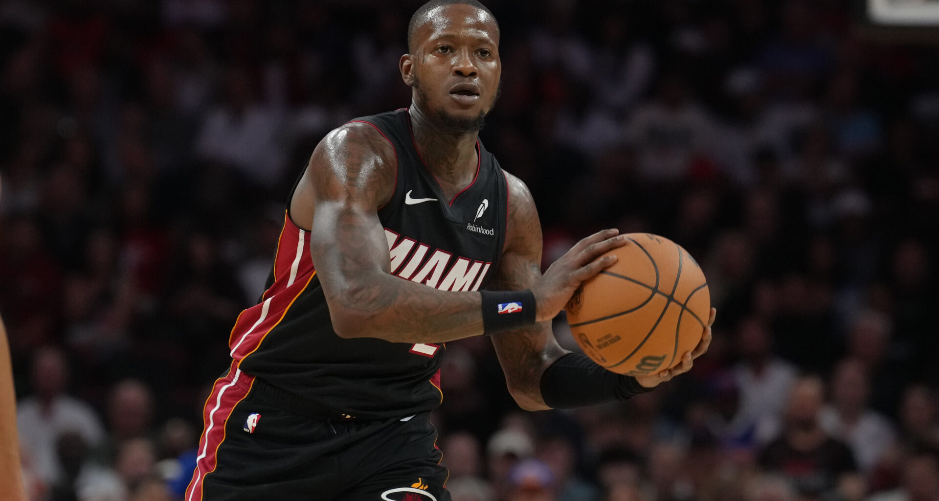 Terry Rozier in a Miami Heat jersey holding a basketball during a game, focused on the court.