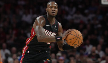 Terry Rozier in a Miami Heat jersey holding a basketball during a game, focused on the court.