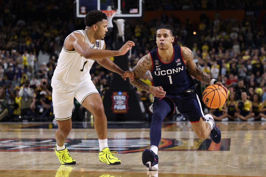 UConn Huskies' Solo Ball dribbling past Michigan Wolverines' Trey McKenney.