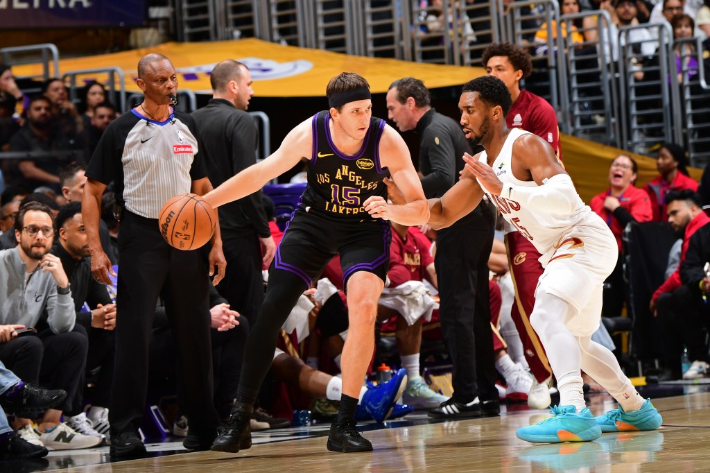 Los Angeles Lakers player Austin Reaves (#15) dribbles the ball against a Cleveland Cavaliers player.