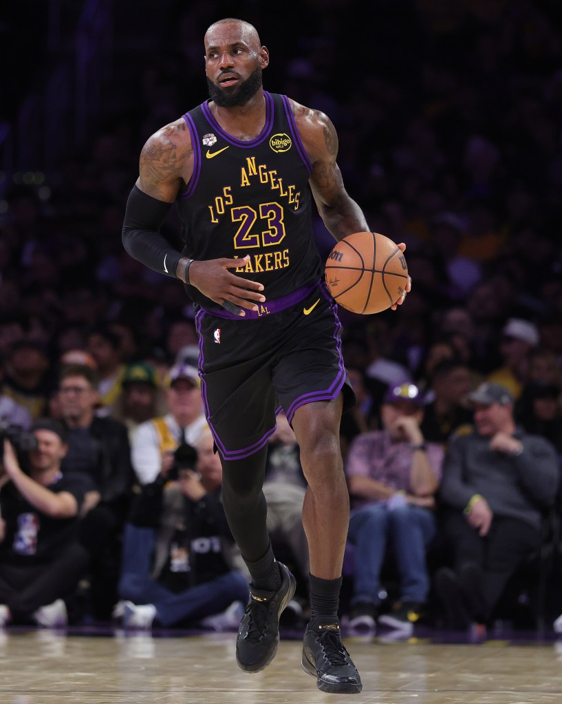LeBron James in a black Lakers uniform with the number 23, holding a basketball on the court.