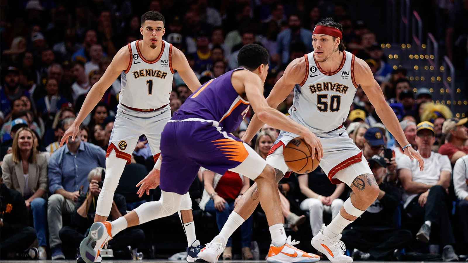 Phoenix Suns guard Devin Booker (1) controls the ball against Denver Nuggets forward Aaron Gordon (50) as forward Michael Porter Jr. (1) defends in the third quarter during game five of the 2023 NBA playoffs at Ball Arena.