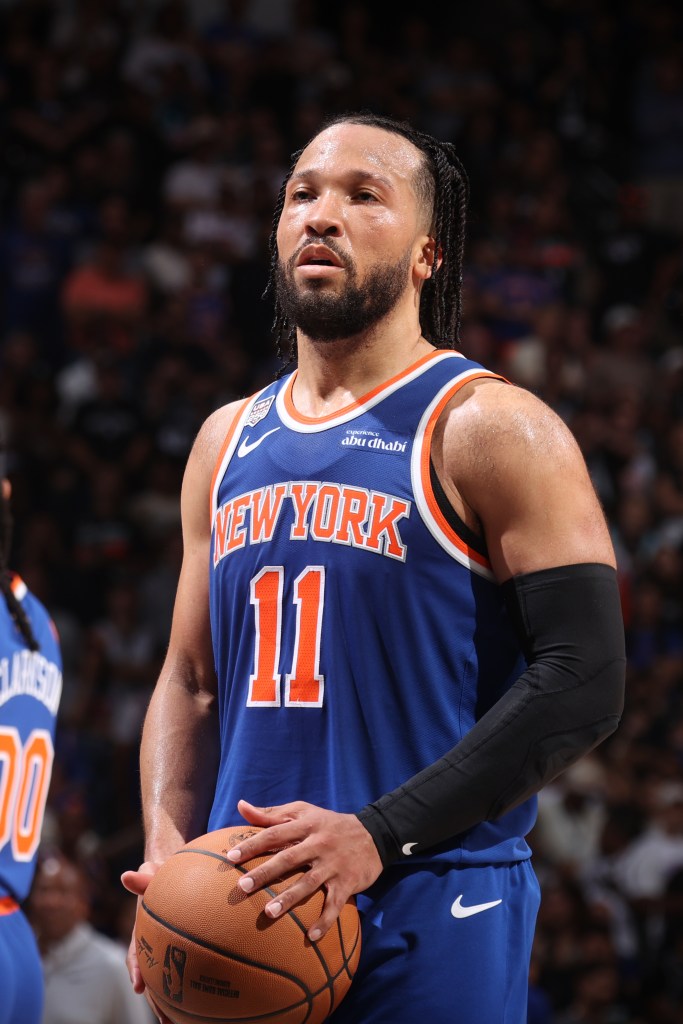 Jalen Brunson in a New York Knicks uniform holding a basketball.