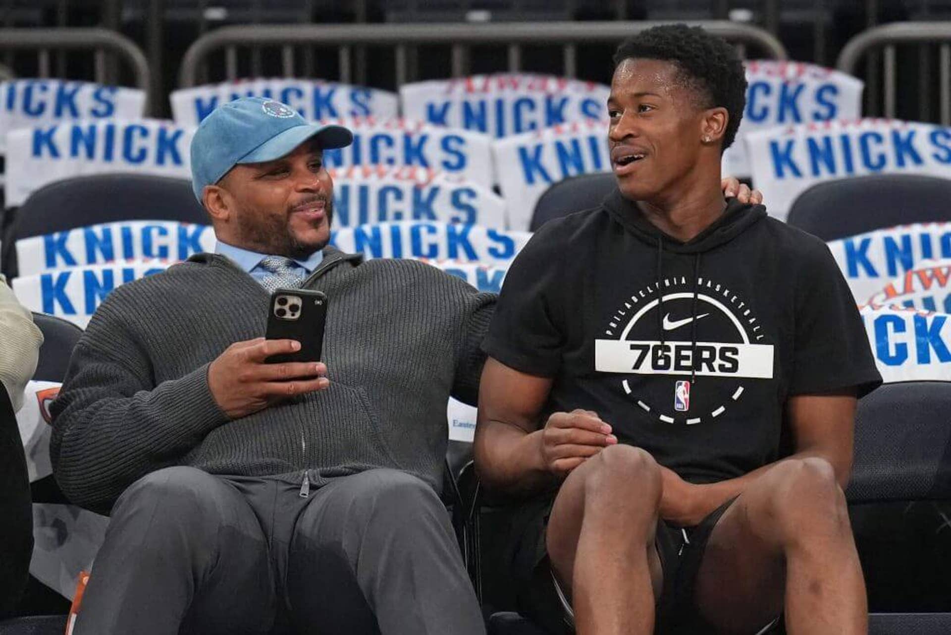 Jameer Nelson and 76ers guard V.J. Edgecombe sit courtside.