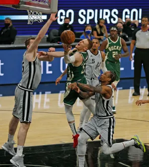 Donte DiVencenzo #0 of the Milwaukee Bucks is fouled by DeMar DeRozan #10 of the San Antonio Spurs.