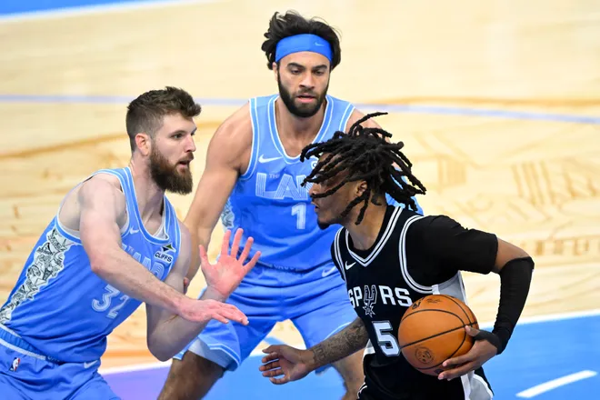 Mar 27, 2025; Cleveland, Ohio, USA; San Antonio Spurs guard Stephon Castle (5) dribbles beside Cleveland Cavaliers guard Max Strus (1) and forward Dean Wade (32) in the third quarter at Rocket Arena. Mandatory Credit: David Richard-Imagn Images