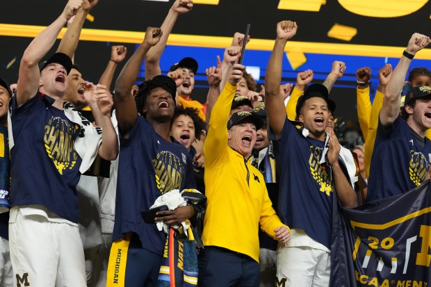 Michigan head coach Dusty May celebrates with his team after defeating UConn in the NCAA college basketball tournament national championship game at the Final Four, Monday, April 6, 2026, in Indianapolis. (AP Photo/Michael Conroy)