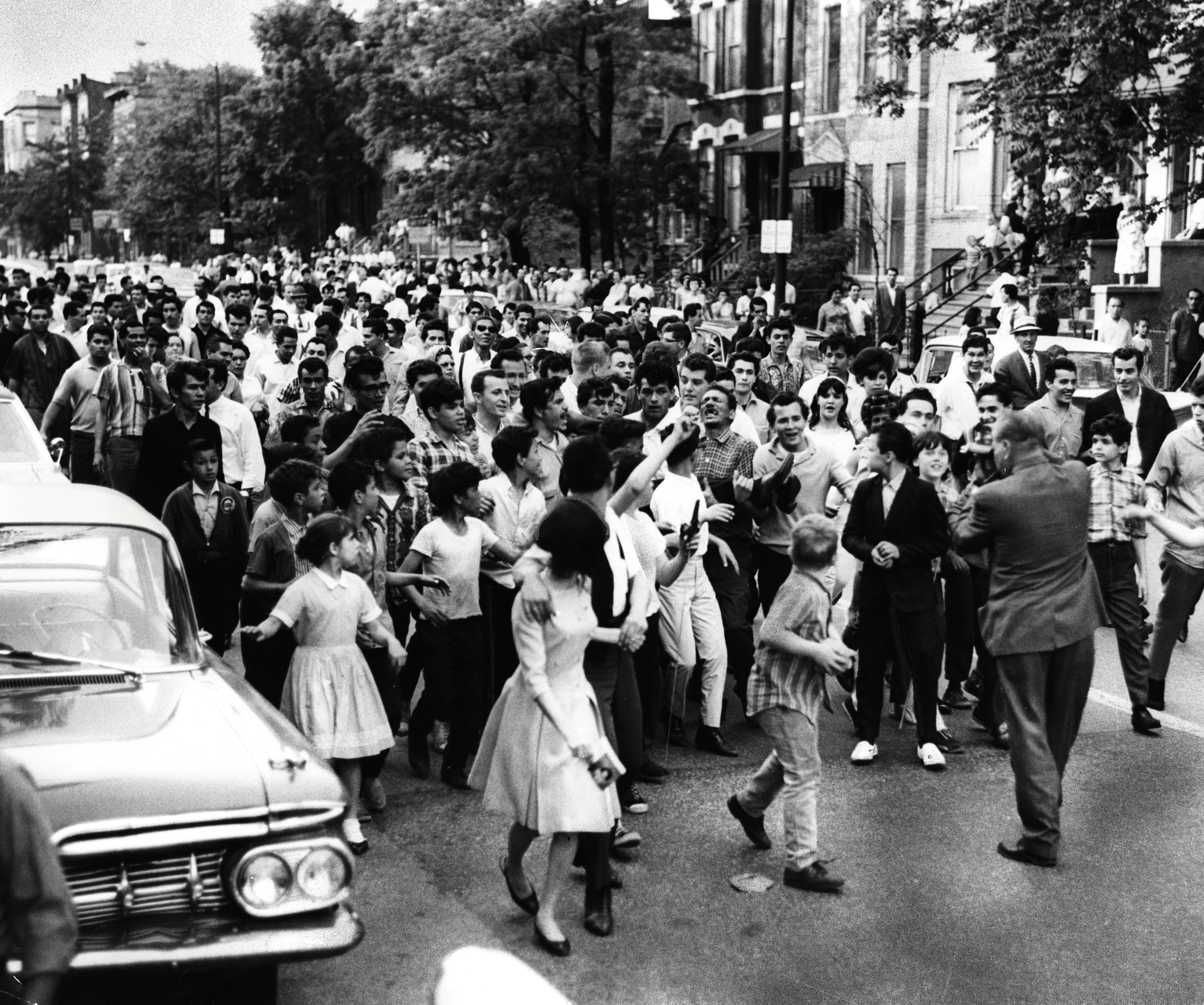 A crowd is joined by children as it carries a...