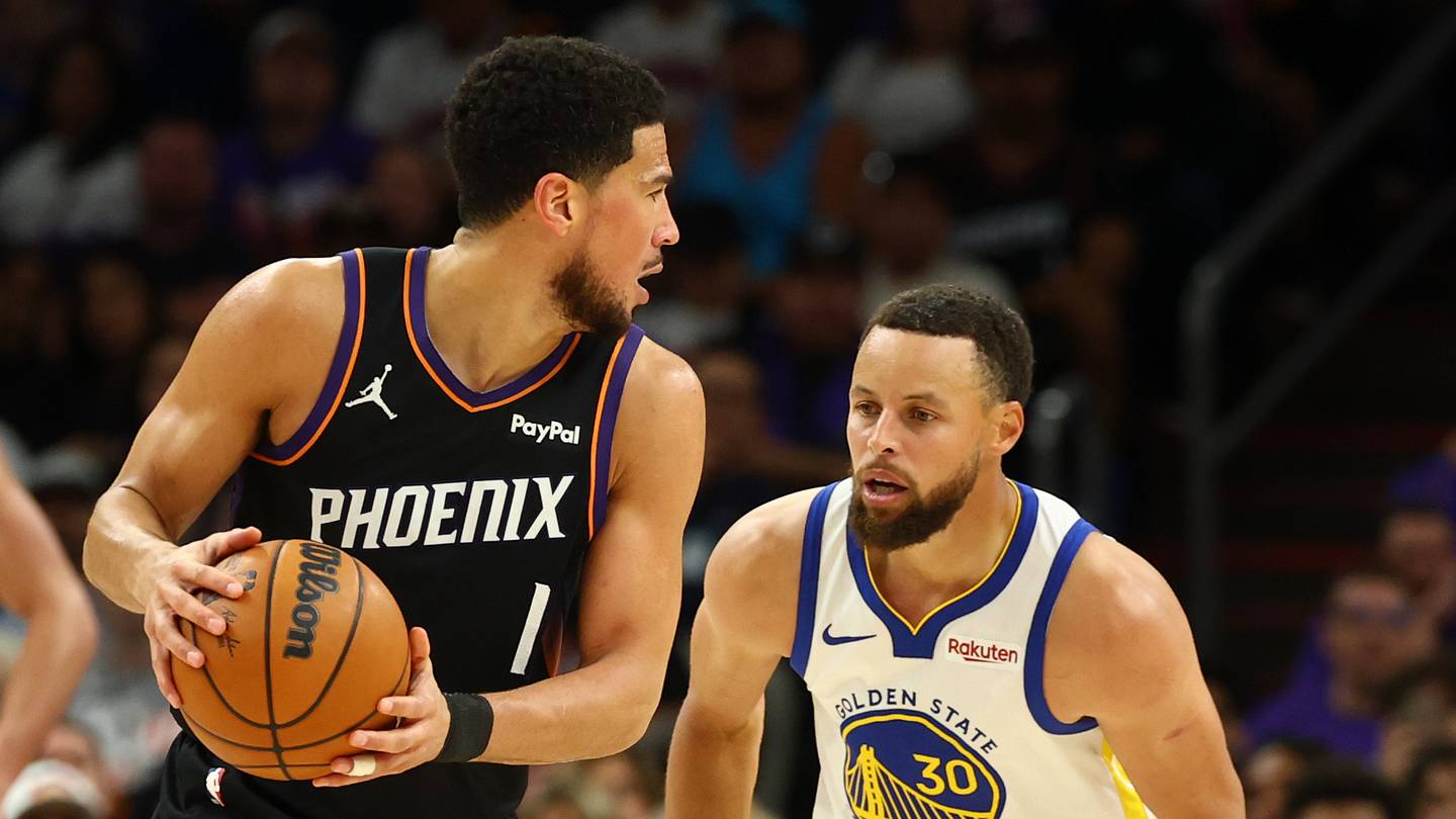 Phoenix Suns guard Devin Booker controls the ball against Golden State Warriors guard Stephen Curry during the second half of the play-in tournament game at Mortgage Matchup Center.