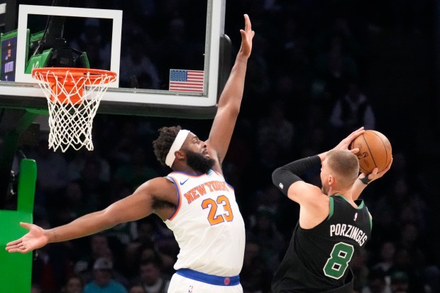 New York Knicks center Mitchell Robinson, left, tries to block a shot by Boston Celtics center Kristaps Porzingis during an NBA game on Monday, Nov. 13, 2023 in Boston. (AP Photo/Charles Krupa)