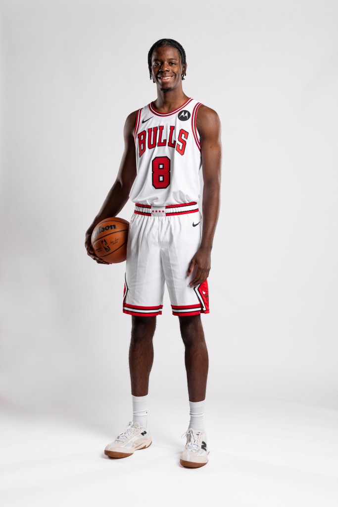 Caleb Wilson, earing his Chicago Bulls uniform, holds a basketball and smiles for a photo shoot.