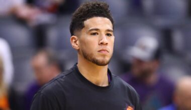 Devin Booker looks on wearing a Suns warmup shirt