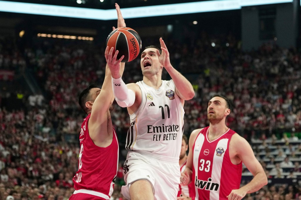Mario Hezonja driving to the basket past Kostas Papanikolaou and Nikola Milutinov during a basketball game.