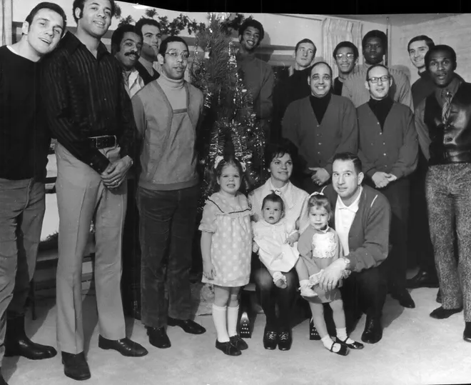 Members of the 1969-'70 Bucks team at Coach Larry Costello's house on December 23, 1969. The Costello family included Leslie Sue (then 4); wife Barbara, who was holding 9-month old Colleen and Larry, with arms around 2-yeawr old Pamela. Others, first row from left: Lenny Chappell, Don Smith, Guy Rodgers, trainer Arnie Garber, business manager Ted Herpel and Flynn Robinson. In rear, from left: Fred Crawford, Dick Cunningham, Lew Alcindor (Behind tree), Bob Greaten, Greg Smith, Bob Dandridge and Jon McGlocklin.