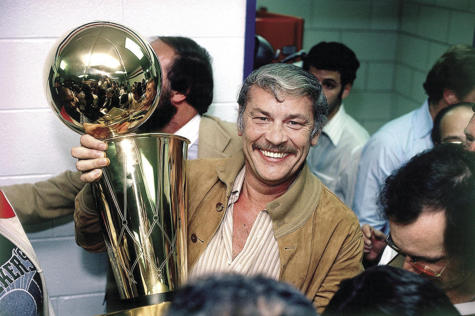 Lakers owner Jerry Buss poses with the NBA championship trophy in 1980.
