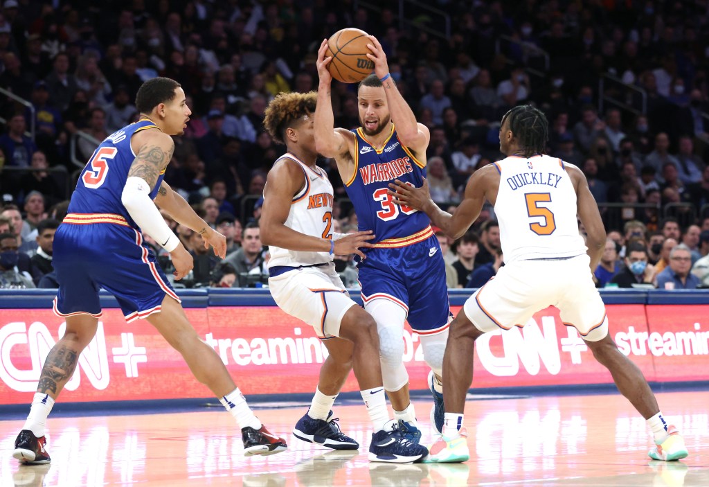 Stephen Curry of the Golden State Warriors being defended by New York Knicks players Immanuel Quickley and Quentin Grimes at Madison Square Garden.