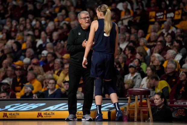 UConn head coach Geno Auriemma and guard Paige Bueckers talk during the first half of an NCAA college basketball game against Minnesota, Sunday, Nov. 19, 2023, in Minneapolis. (AP Photo/Abbie Parr)