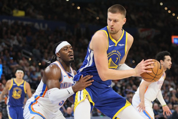 Golden State Warriors center Kristaps Porzingis (7) looks for an outlet against Oklahoma City Thunder guard Luguentz Dort, left, during the second half of an NBA basketball game Saturday, March 7, 2026, in Oklahoma City. (AP Photo/Nate Billings)