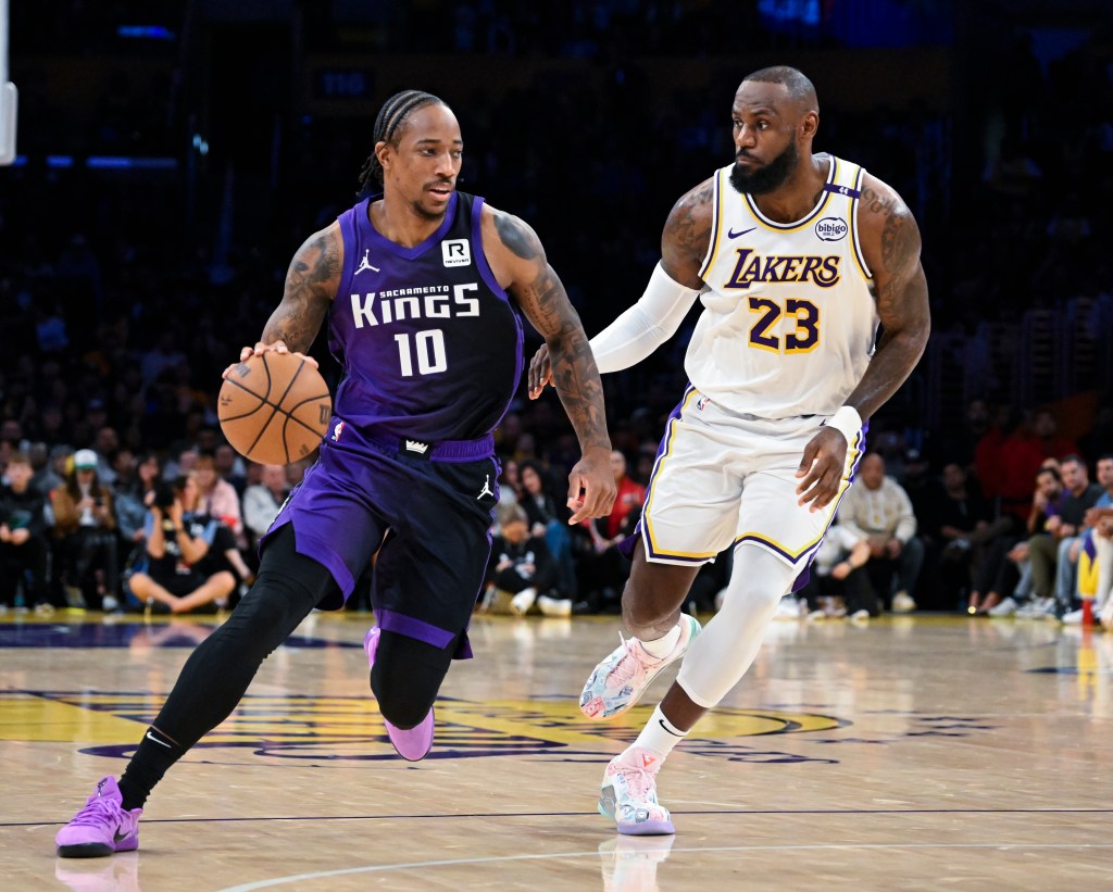Two basketball players, one in a purple Kings uniform dribbling and one in a white Lakers uniform defending.
