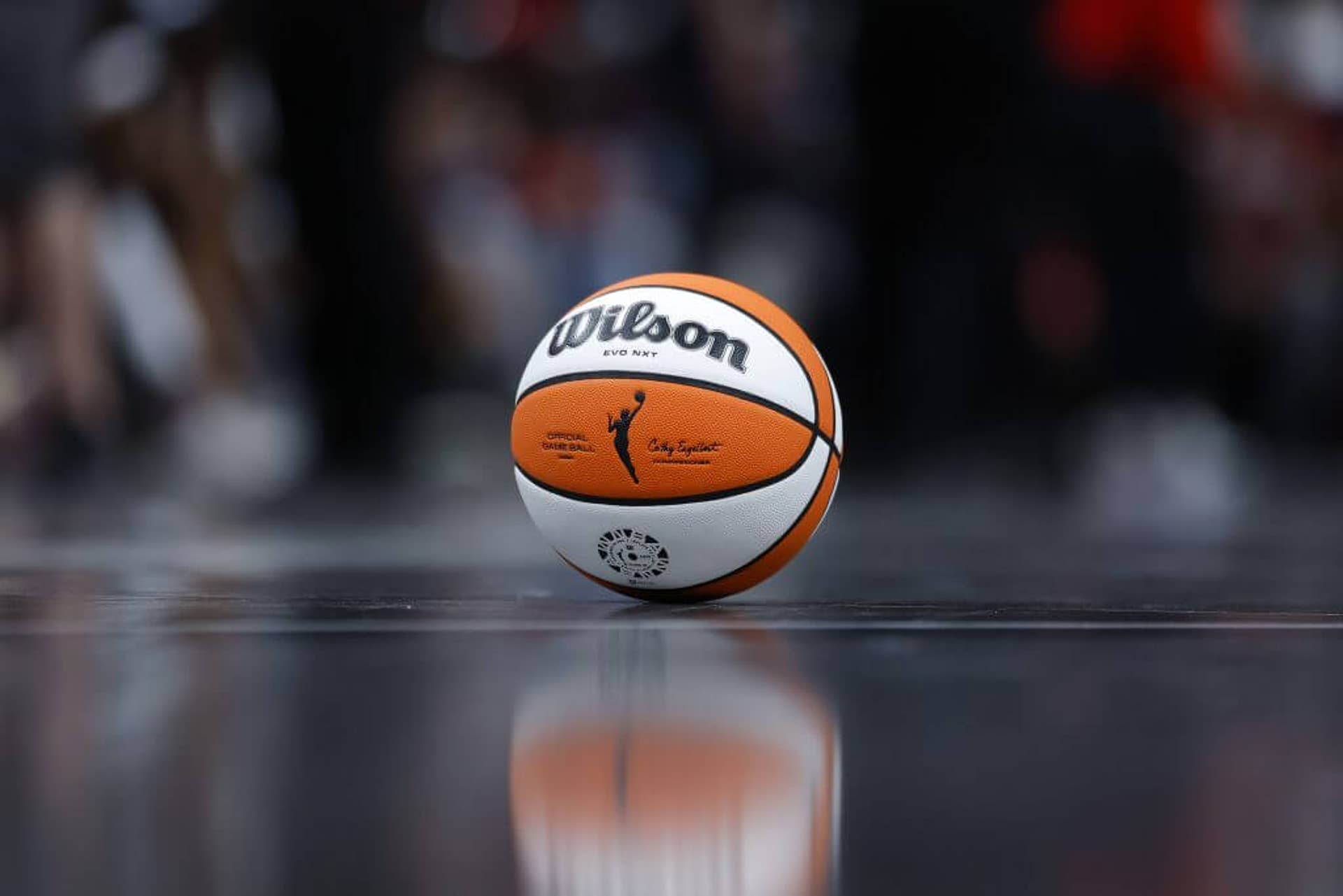 A Wilson WNBA basketball rests on a basketball court.