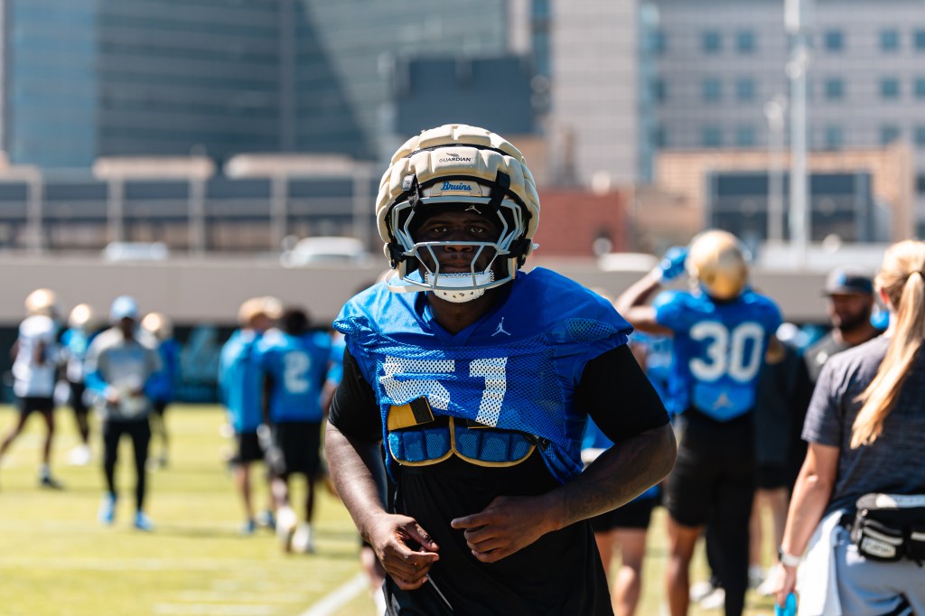 Football player Hendrick Trent in a blue jersey with the number 57 and a Bruins helmet.