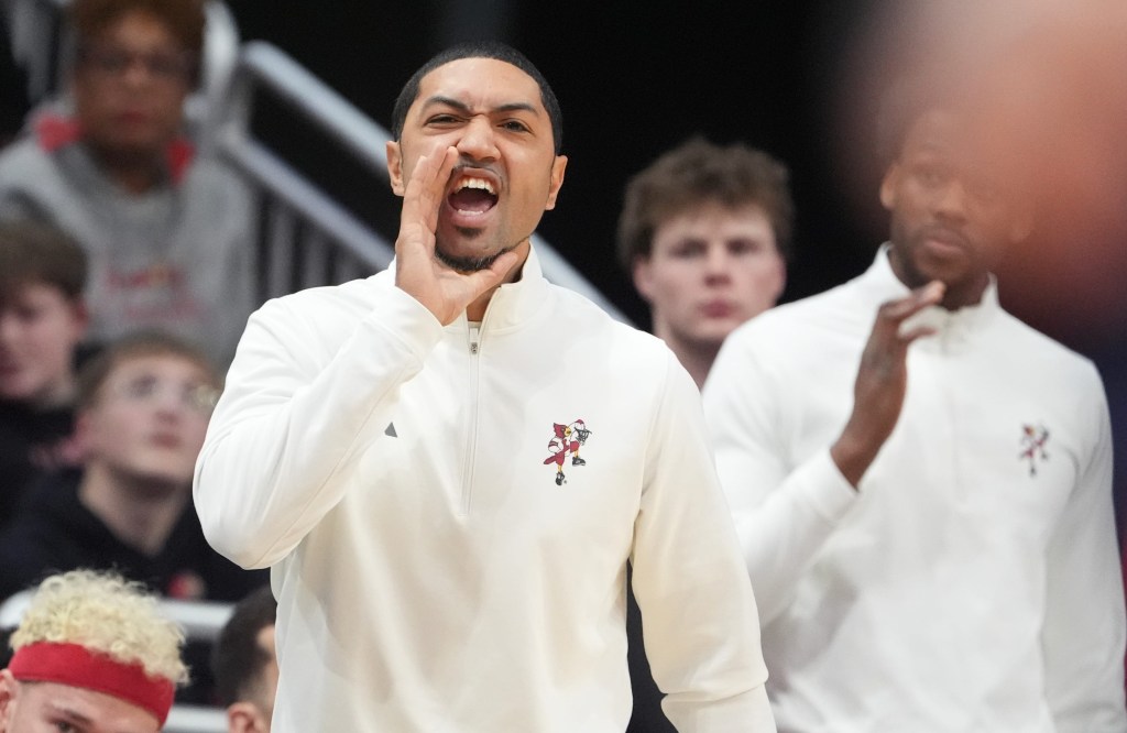 Peyton Siva coaching his team in a white long-sleeved shirt with a small red and white mascot logo on the left chest.