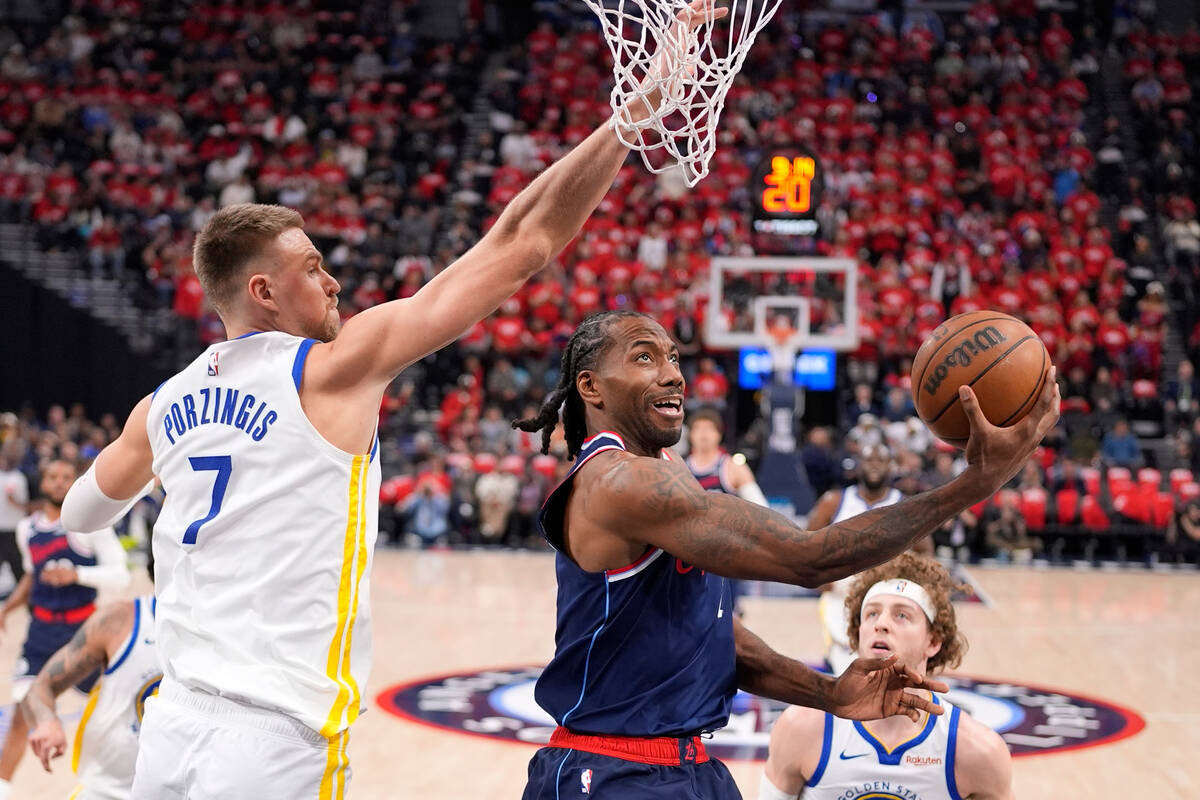 LA Clippers forward Kawhi Leonard, center, shoots as Golden State Warriors center Kristaps Porz ...
