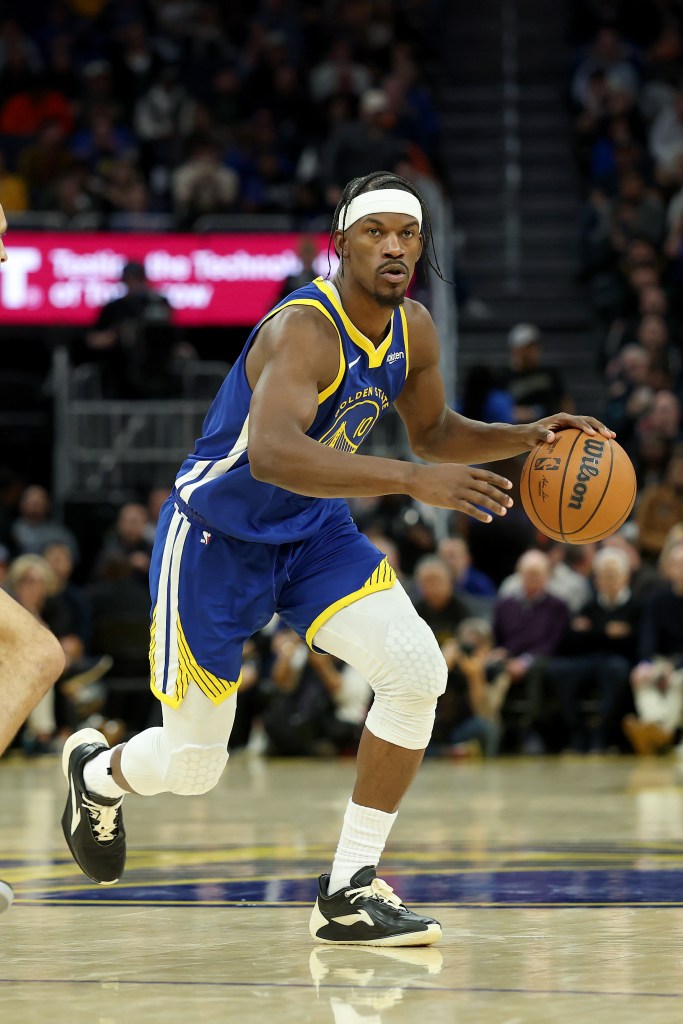 Basketball player in a blue and yellow jersey dribbling a basketball.