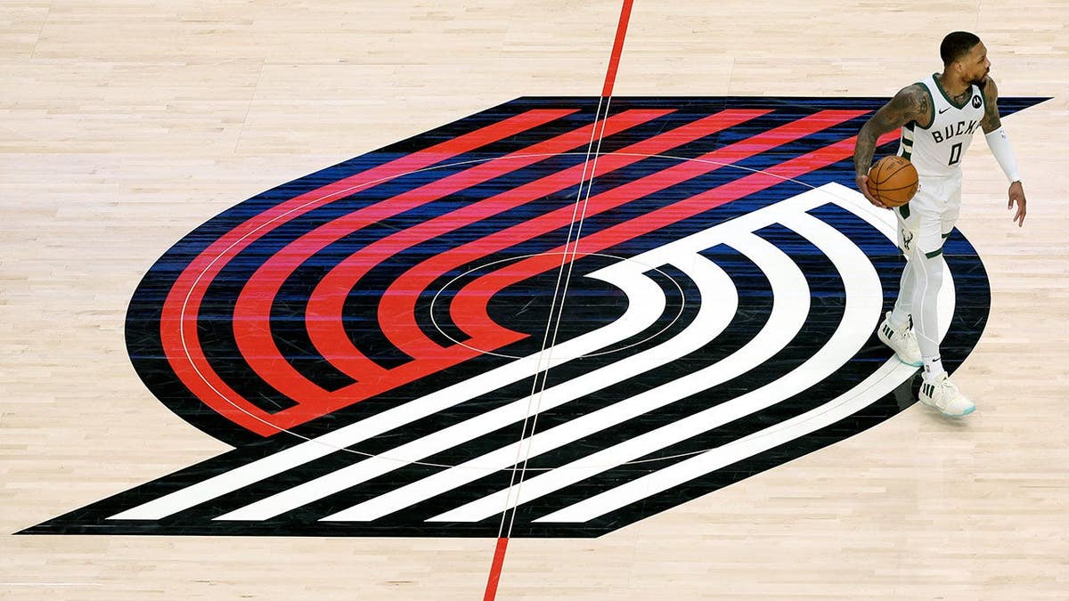 Damian Lillard dribbles the ball on the Portland Trail Blazers center court logo during an NBA game.