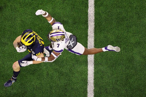 Michigan's Colston Loveland, left, is tackled by Washington's Dominique Hampton...