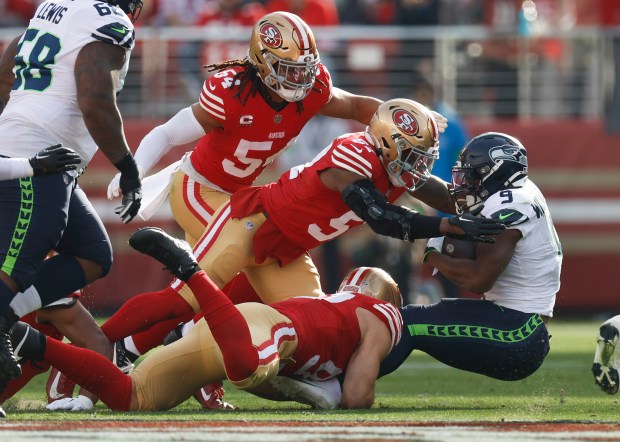 San Francisco 49ers' Dre Greenlaw (57), Fred Warner (54) and Nick Bosa (97) tackle Seattle Seahawks' Kenneth Walker III (9) in the first quarter at Levi's Stadium in Santa Clara, Calif., on Sunday, Dec. 10, 2023. (Nhat V. Meyer/Bay Area News Group)