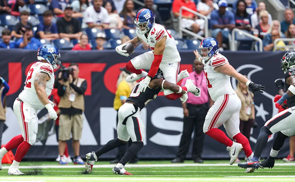 Aug 17, 2024; Houston, Texas, USA; New York Giants tight end Theo Johnson (47) leaps with the ball as Houston Texans safety Jimmie Ward (20) defends during the first quarter at NRG Stadium. Mandatory Credit: Troy Taormina-USA TODAY Sports