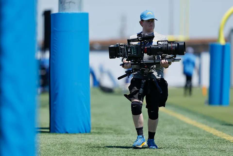A member of the Chargers' content team films players taking part in rookie minicamp.