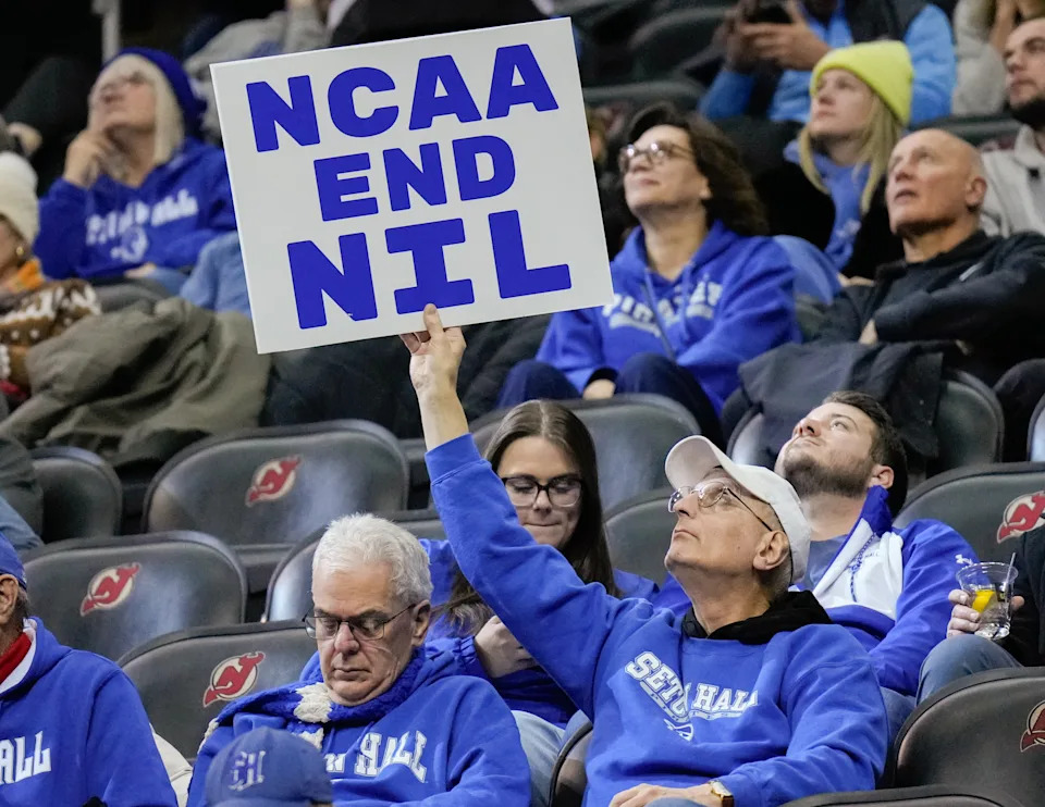 NEWARK, NJ - JANUARY 21: A fan holds a sign about name, image and likeness (NIL) payments for college athletes during a college basketball game between the Seton Hall Pirates and the Marquette Golden Eagles at Prudential Center on January 21, 2025 in Newark, New Jersey. (Photo by Porter Binks/Getty Images)