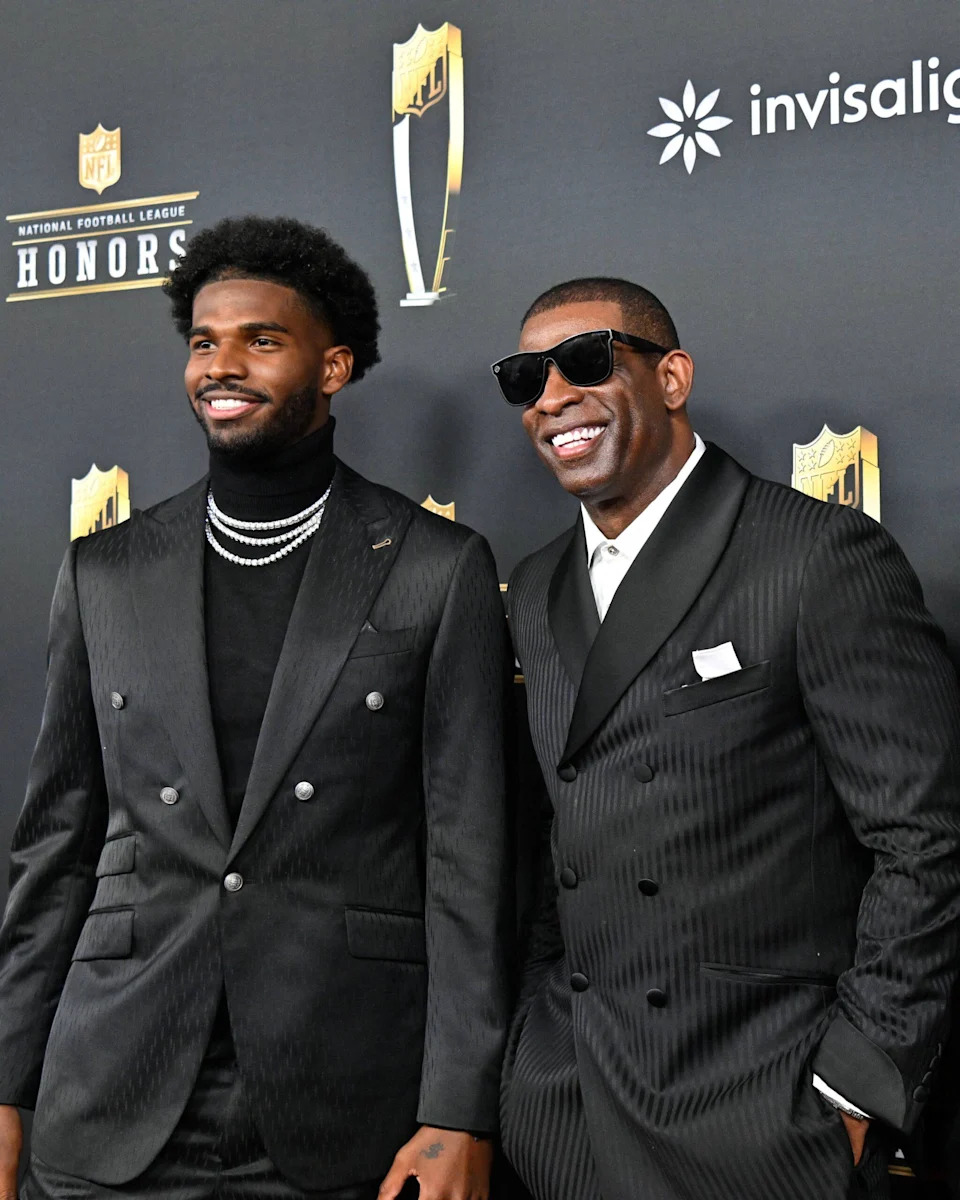 Shedeur Sanders posing with father Deion Sanders on the red carpet.