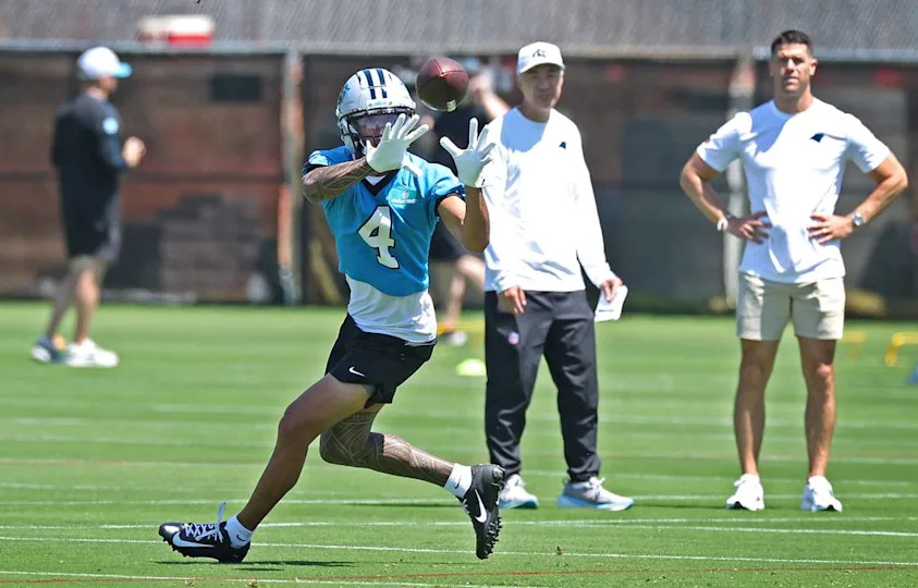 Carolina Panthers rookie wide receiver Tetairoa McMillan, left, keeps his eyes on the ball as he catches a pass during the team’s rookie minicamp practice on Friday, May 9, 2025. At right, head coach Dave Canales watches. JEFF SINER/jsiner@charlotteobserver.com