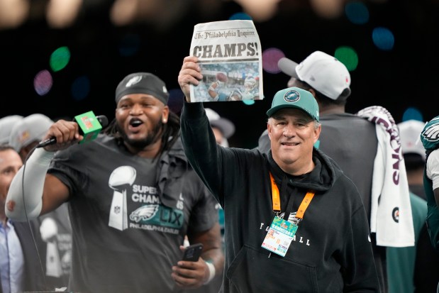 Eagles defensive coordinator Vic Fangio lifts a newspaper that says, "Champs," with defensive tackle Jalen Carter after winning the Super Bowl on Feb. 9, 2025, in New Orleans. (AP Photo/Doug Benc)