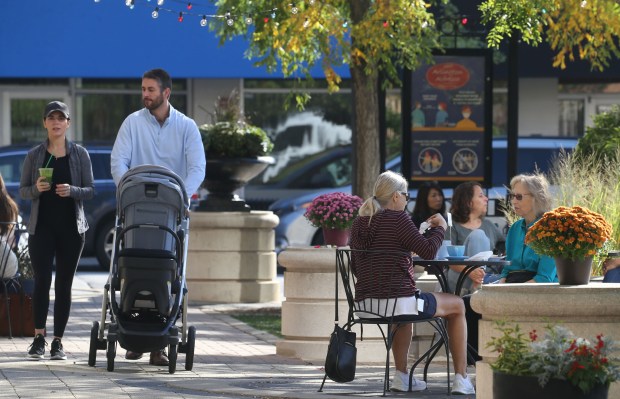 Customers sit outdoors in the Arlington Alfresco area, enjoying conversation...