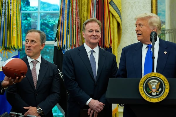 Washington Commanders owner Josh Harris, from left, and NFL Commissioner Roger Goodell watch as a football is presented to President Donald Trump during an event to announce that the 2027 NFL Draft will be held on the National Mall, in the Oval Office of the White House, Monday, May 5, 2025, in Washington. (AP Photo/Alex Brandon)
