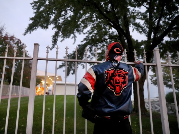 Selso Nuñez, of Palatine, dressed in Bears garb, peeks over...
