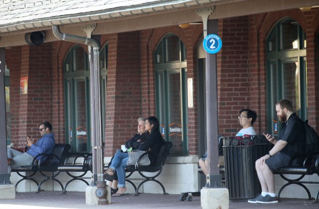 People wait for a Metra train in downtown Arlington Heights...