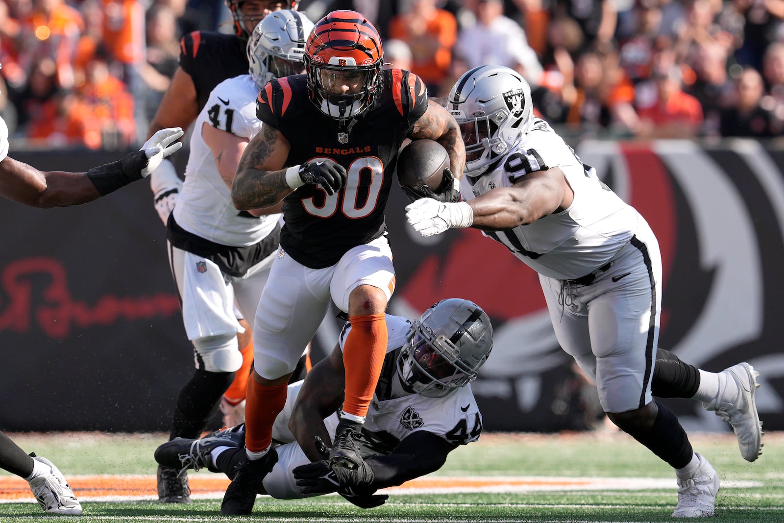 Cincinnati Bengals running back Chase Brown (30) runs against Las Vegas Raiders linebacker Robert Spillane (41), defensive end K'Lavon Chaisson (44) and defensive tackle Matthew Butler (91) during the first half ofan NFL football game in Cincinnati, Sunday, Nov. 3, 2024. (AP Photo/Jeff Dean)