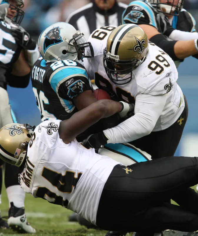 Nov 25, 2007, Carolina Panthers running back DeShaun Foster (26) is tackled by New Orleans Saints defensive tackle Hollis Thomas (99) and defensive end Charles Grant (94). Mandatory Credit: Bob Donnan-Imagn Images
