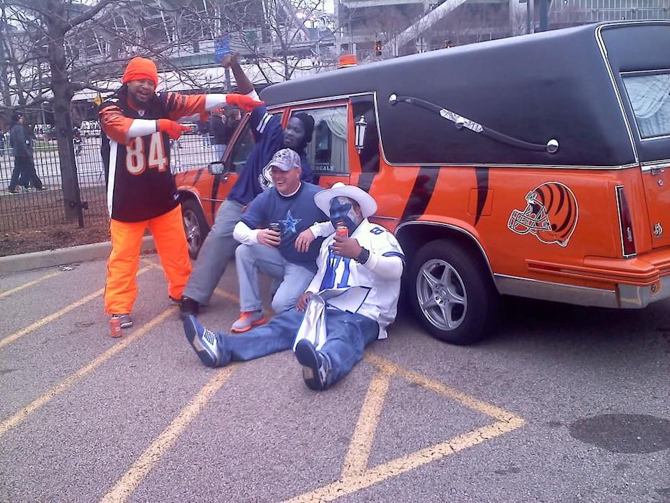 Dallas Cowboys and Bengals fans surround the hearse on game day.