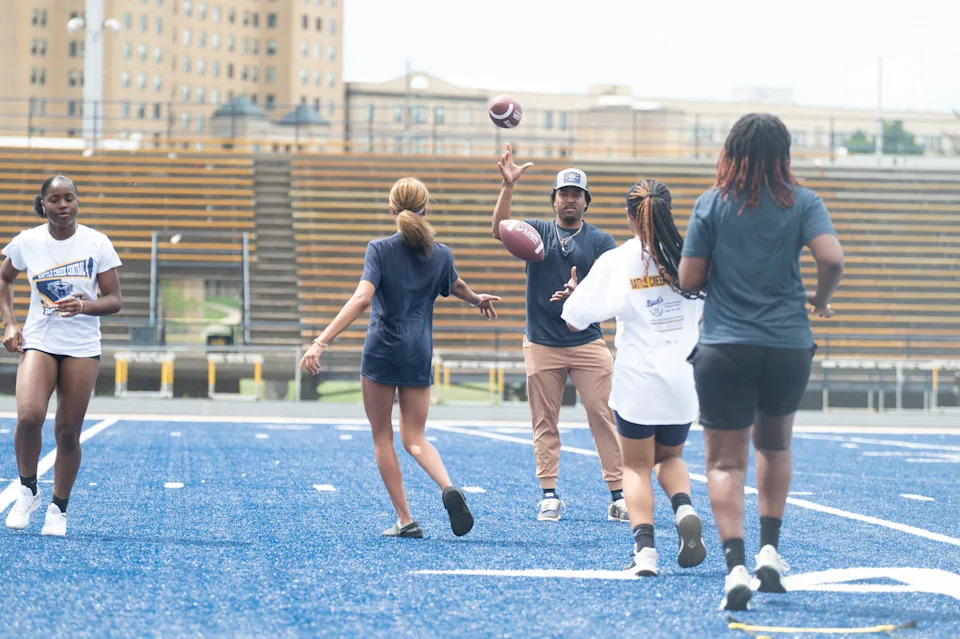 Battle Creek Central coach Mario Brown throws to players during a flag football practice at Battle Creek Central High School on Thursday, May 15, 2025.